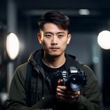 朝桐光资讯站摄影编辑田中悠的头像，年轻男性摄影师手持相机，专业工作室背景